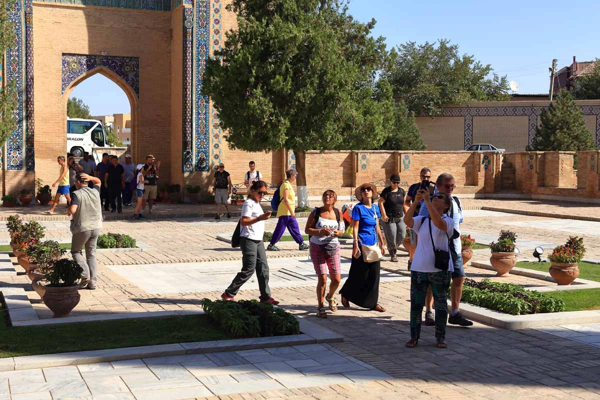 Historic courtyard visit Visitors walking through a courtyard with arches, garden paths and historic brickwork