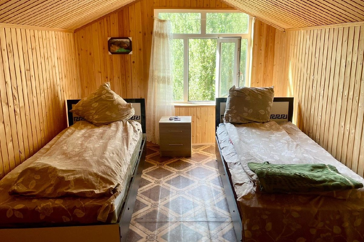 Chambre à deux lits aux murs lambrissés dans la maison d’hôtes