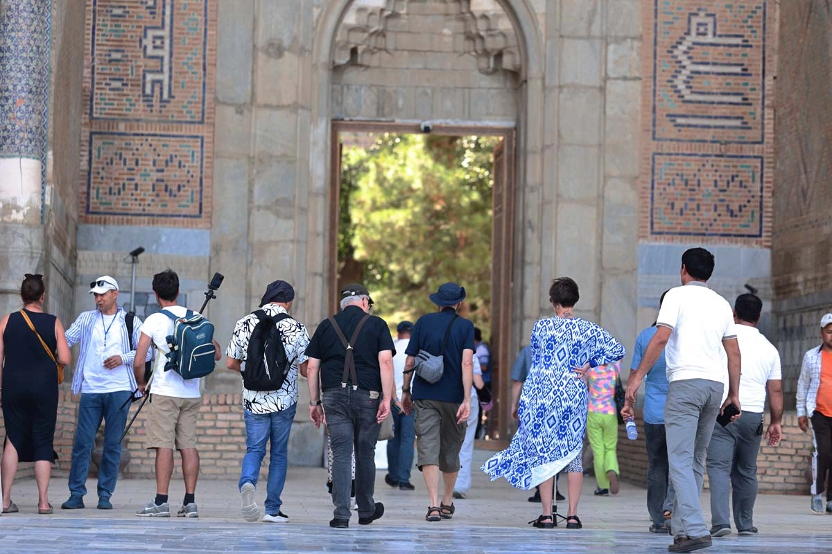 Group entering a historic monument Visitors walking through a decorated stone portal at a historic monument in Uzbekistan