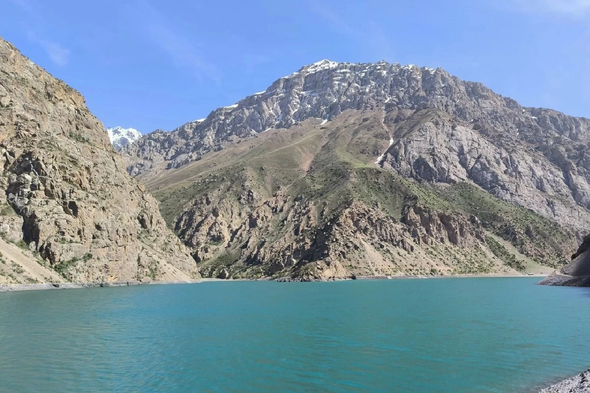 Göller zincirinin üstündeki Hazorchashma Uzakta karlı zirveler görünen yüksek kayalık dağların altındaki turkuaz Hazorchashma Gölü