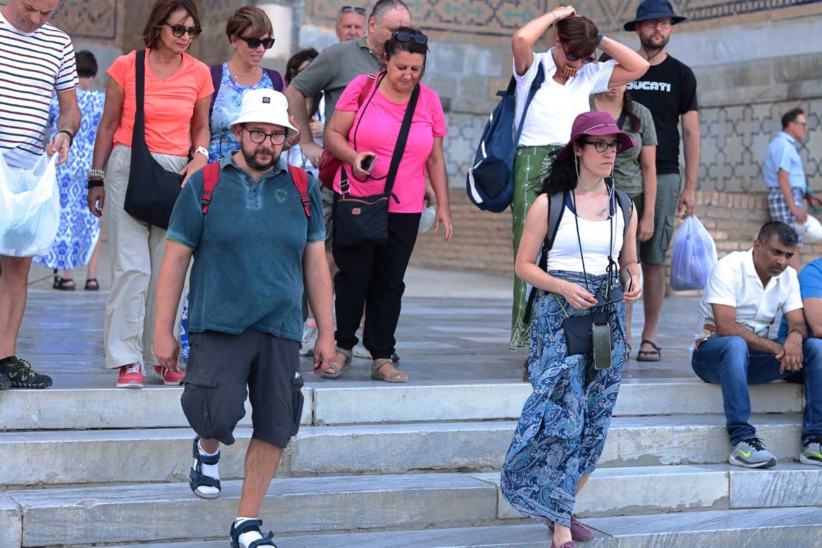 Group moving between sightseeing stops Travelers walking down steps near a historic monument in Uzbekistan