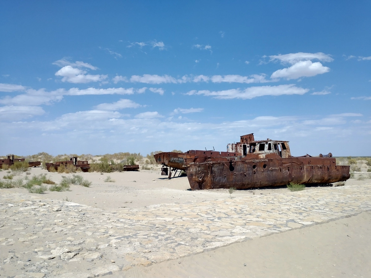 Rusted boats beside the walking area in Muynak Rusted boats beside a paved walking area at Muynak Ship Cemetery