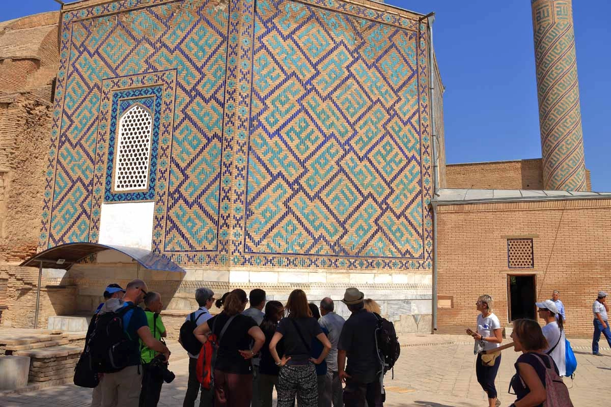 Historic tiled facade with visitors Group viewing a large turquoise tiled facade at a historic monument in Uzbekistan
