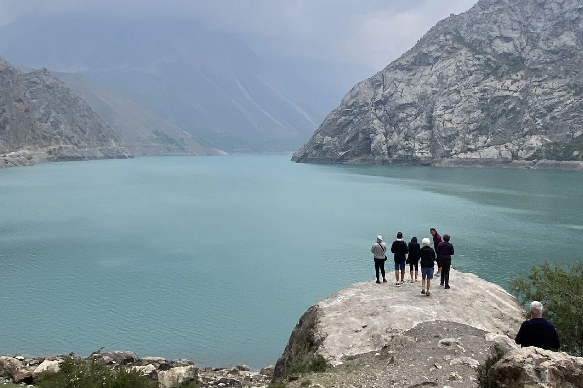Haft Kul göllerinden birinin kıyısındaki gezginler Turkuaz dağ gölü kıyısındaki büyük bir kaya üzerinde duran gezginler