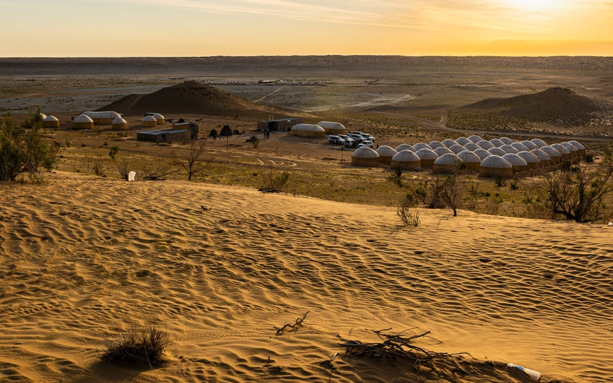 Rows of white yurts at the Darvaza desert camp near sunset