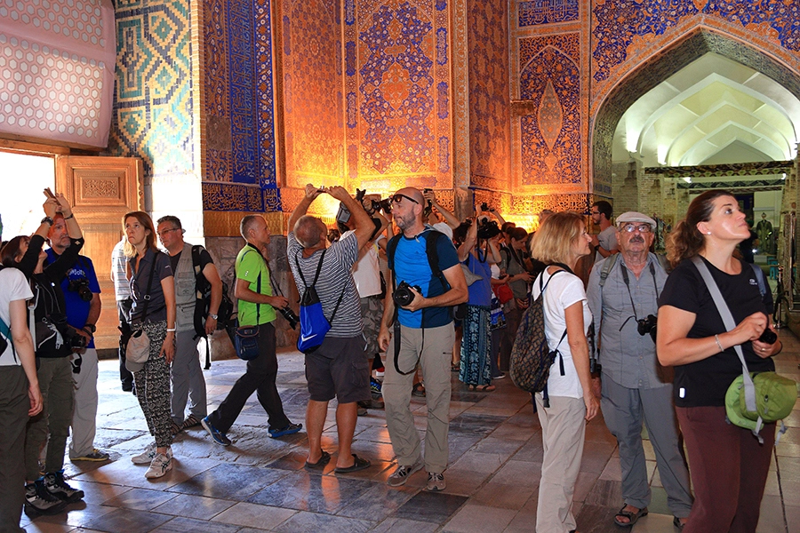 Small group of tourists viewing the ornate tile work inside a historic Samarkand madrasah during an Uzbekistan tour