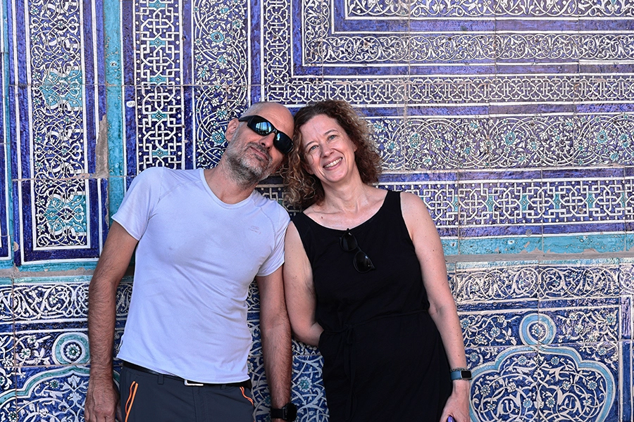 Couple posing happily in front of the exquisite blue tile mosaic work at Tash Hauli Palace in Khiva