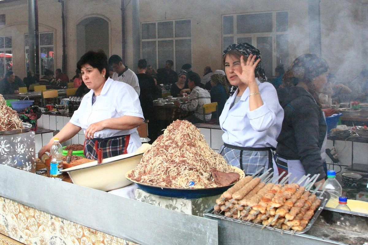 Vendors at a counter with a large platter of naryn and shashlik