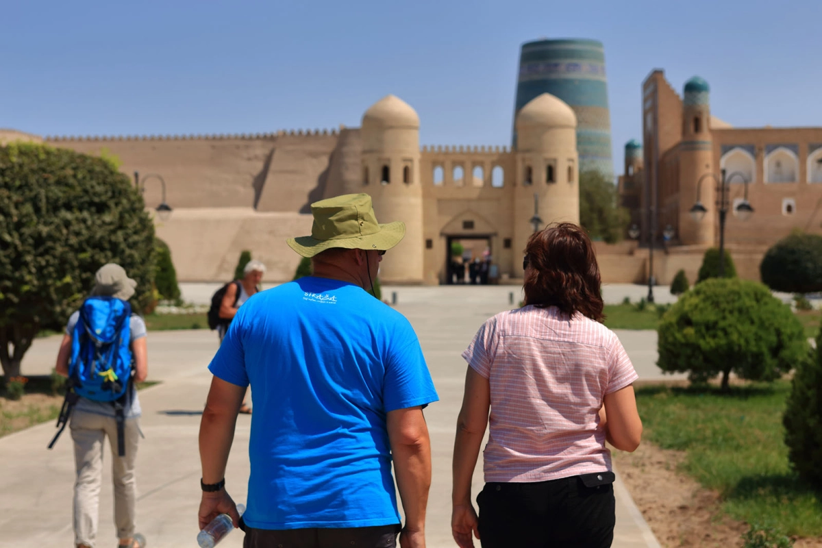 Tourists walking toward the West Gate of Ichan Kala with Kalta Minor in the background, Khiva Uzbekistan
