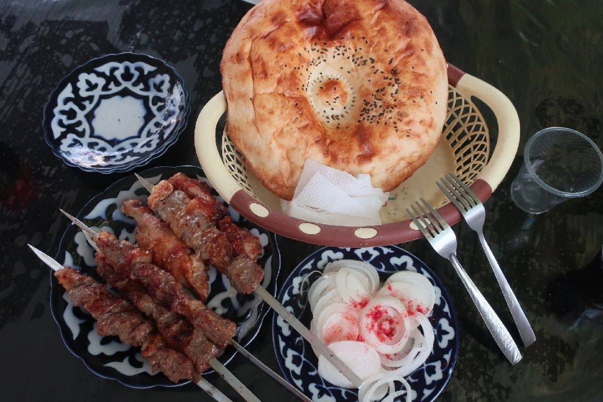 Flatbread, shashlik and sliced onions on a laid table