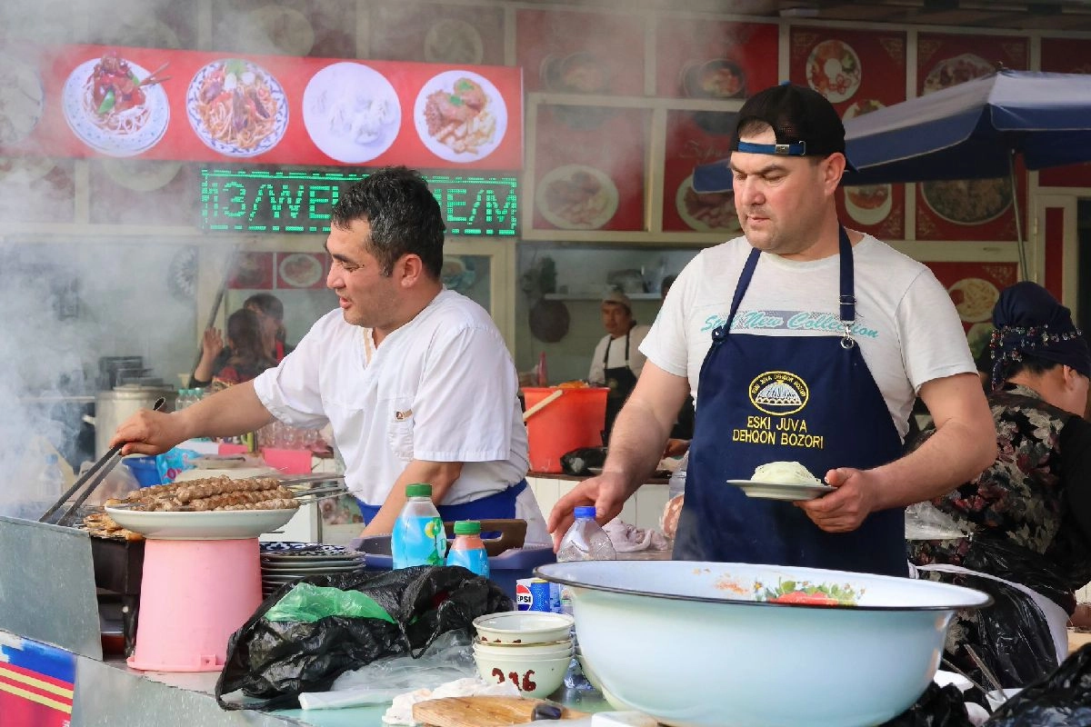 Cooks at a grill among the prepared-food stalls