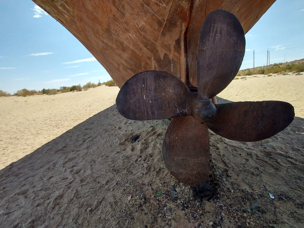 Rusted ship propeller at Muynak Ship Cemetery Rusted ship propeller below an abandoned boat at Muynak Ship Cemetery